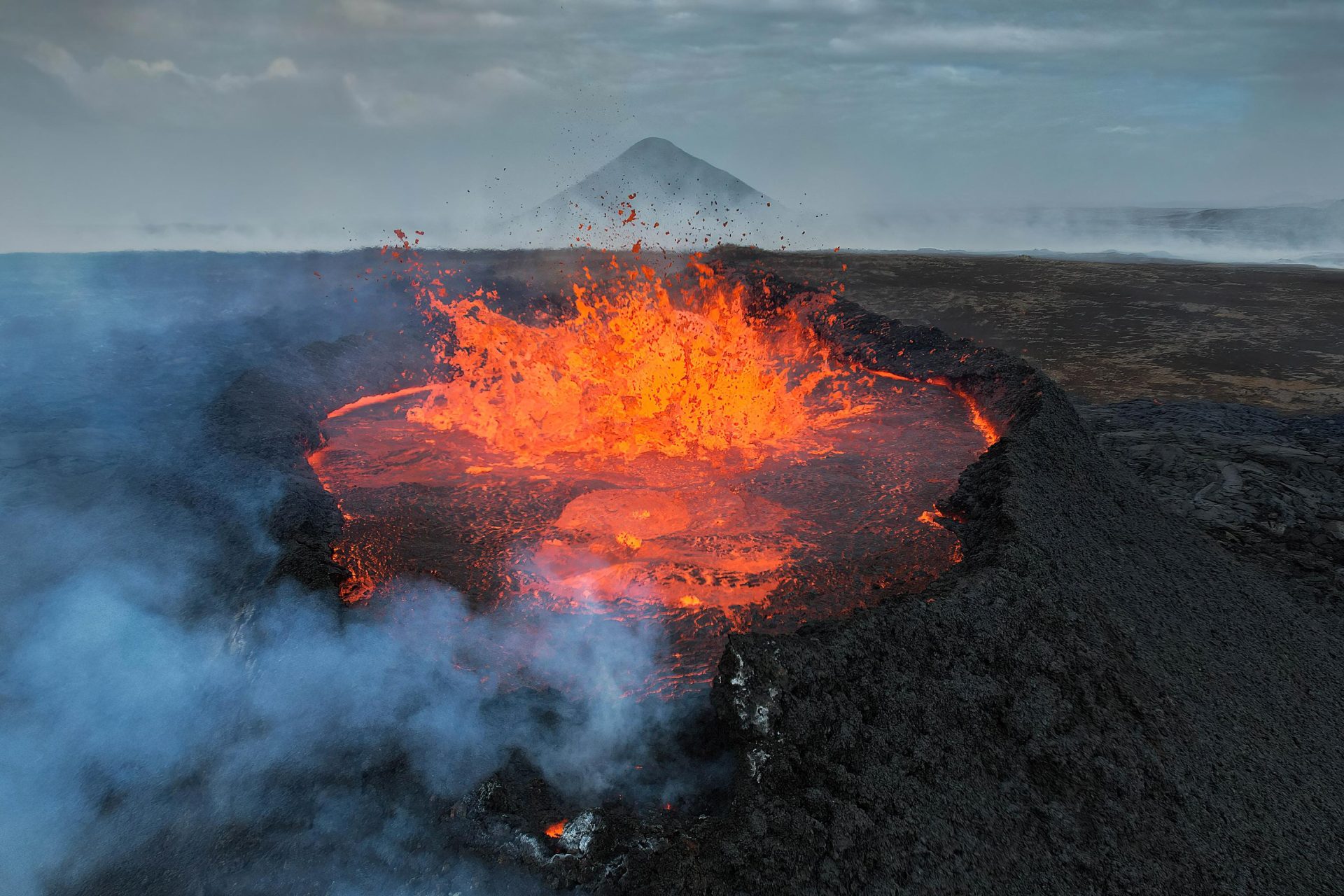 Lava and smoke emerge from a snowy Mount Etna